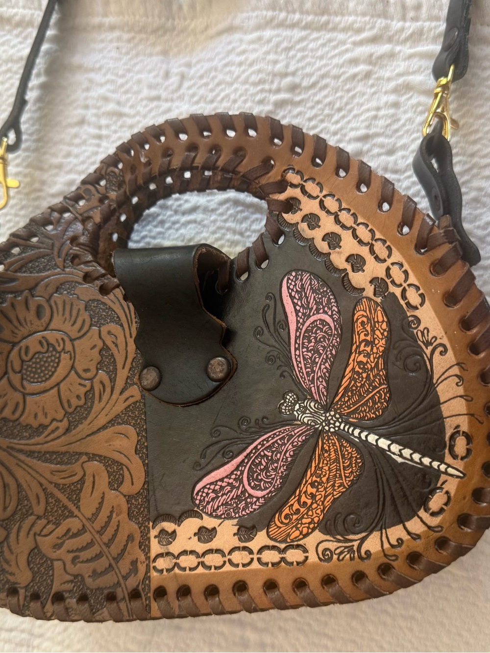brown leather circular handbag with a hand-tooled floral pattern and a